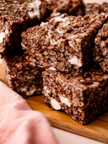 Close-up of gooey, chocolate rice crispy treats on a wooden board.