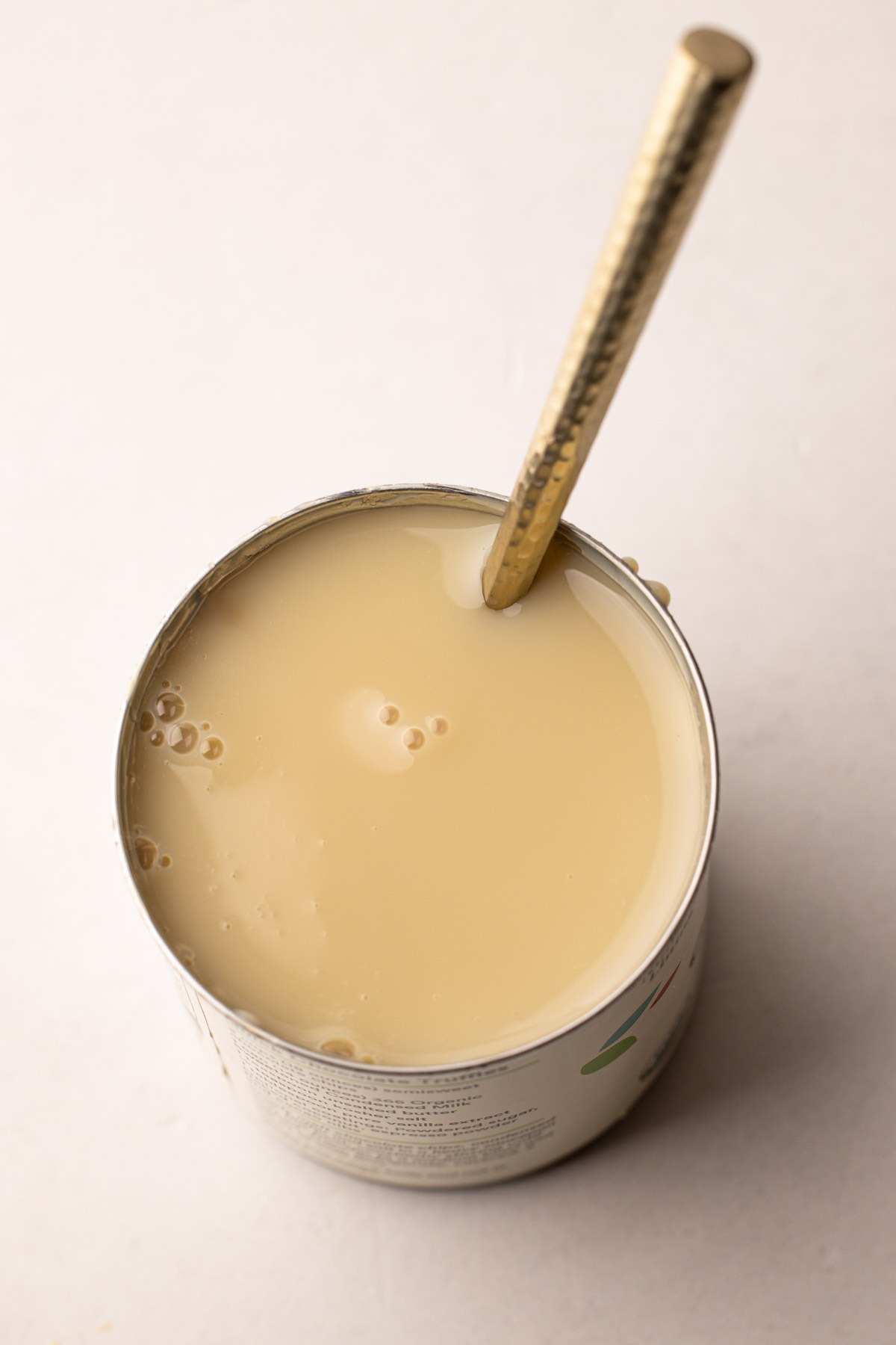 Open can of sweetened condensed milk with a spoon.