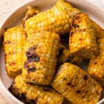 Grilled corn with a golden, charred exterior, seasoned with parmesan garlic butter.