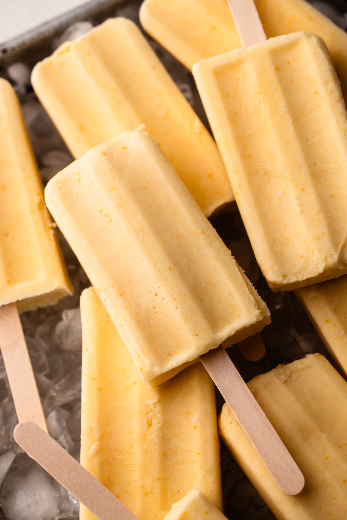 Orange Creamsicle Popsicles arranged on a bed of ice.