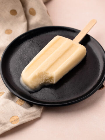 Pineapple coconut popsicle with a bite taken out.