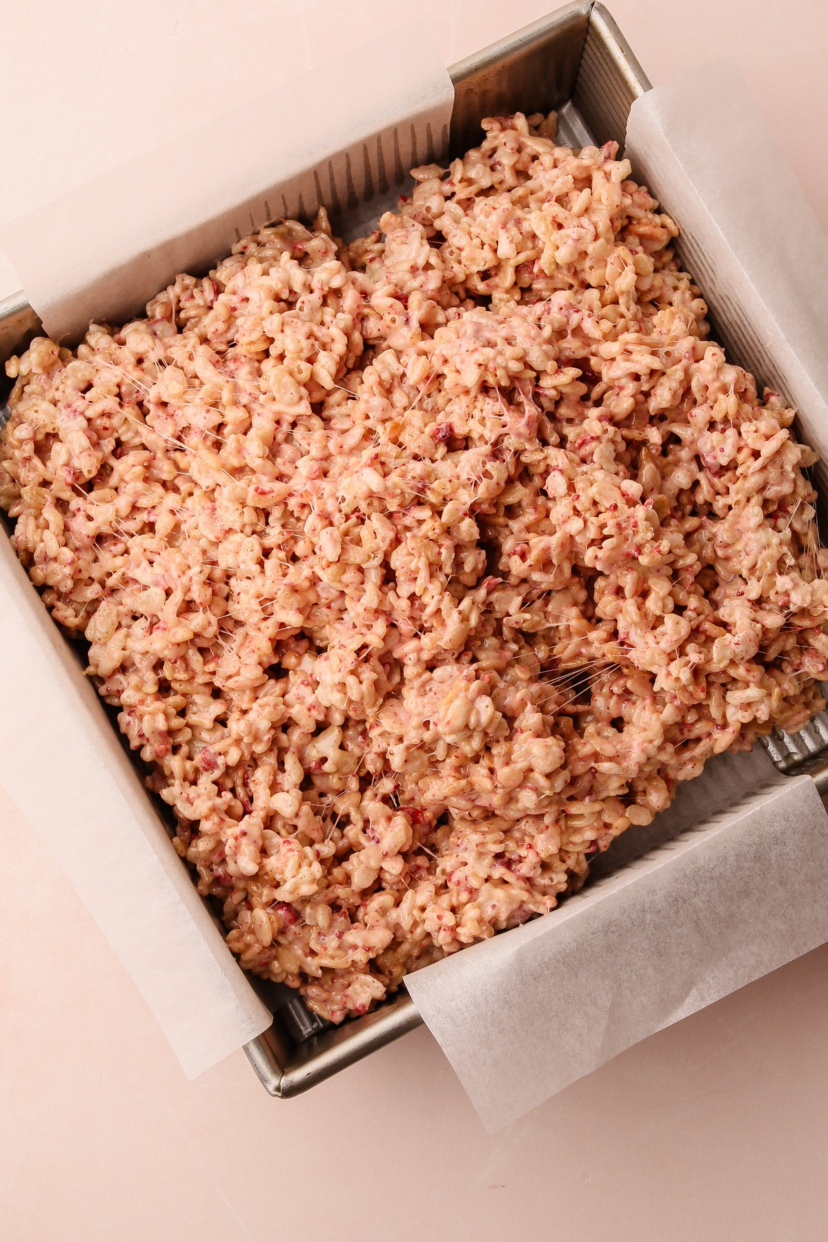 Strawberry rice crispy treats mixture spread in a baking pan.