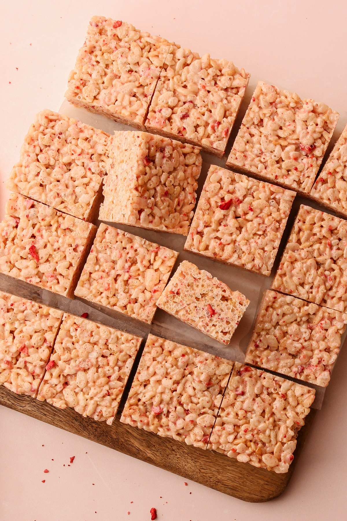 Sliced strawberry rice crispy treats on a cutting board.