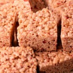 Sliced strawberry rice crispy treats on a cutting board.