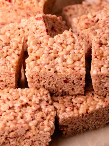 Sliced strawberry rice crispy treats on a cutting board.