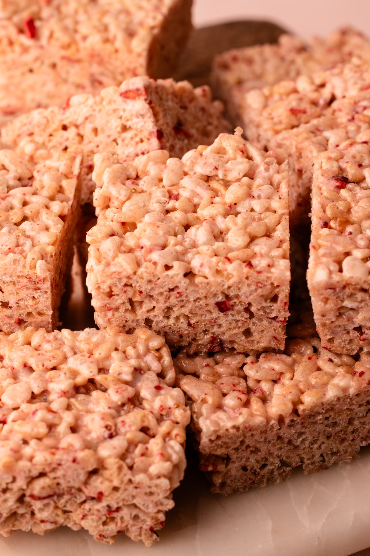 Sliced strawberry rice crispy treats on a cutting board.