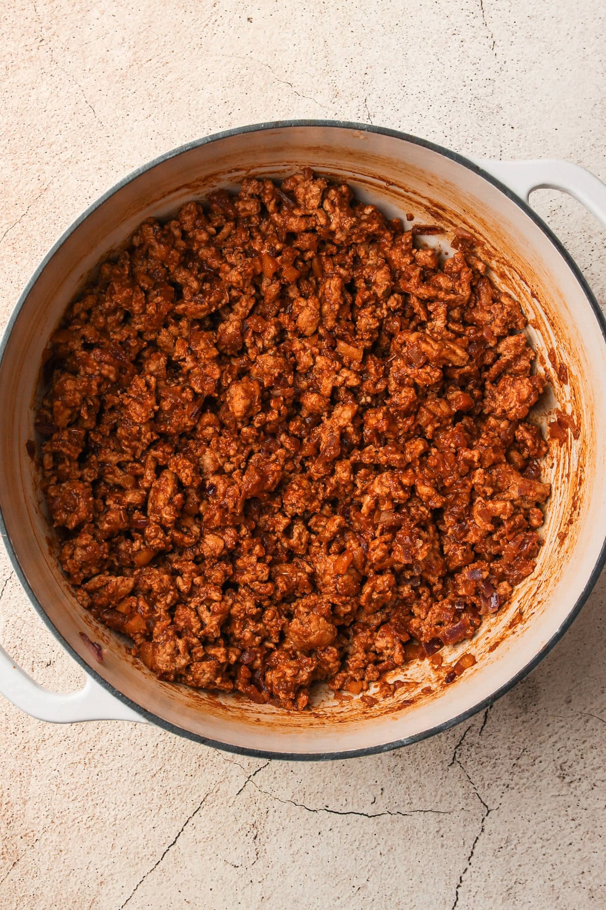 Seasoned ground turkey in a Dutch oven, coated in a rich chili spice blend for a turkey chili.