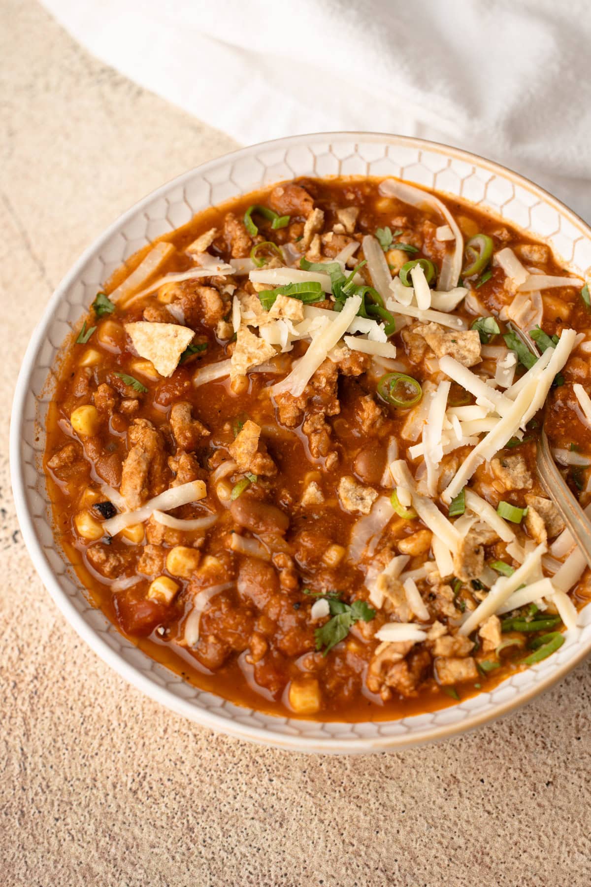 A bowl of turkey chili with corn, beans and tomatoes.