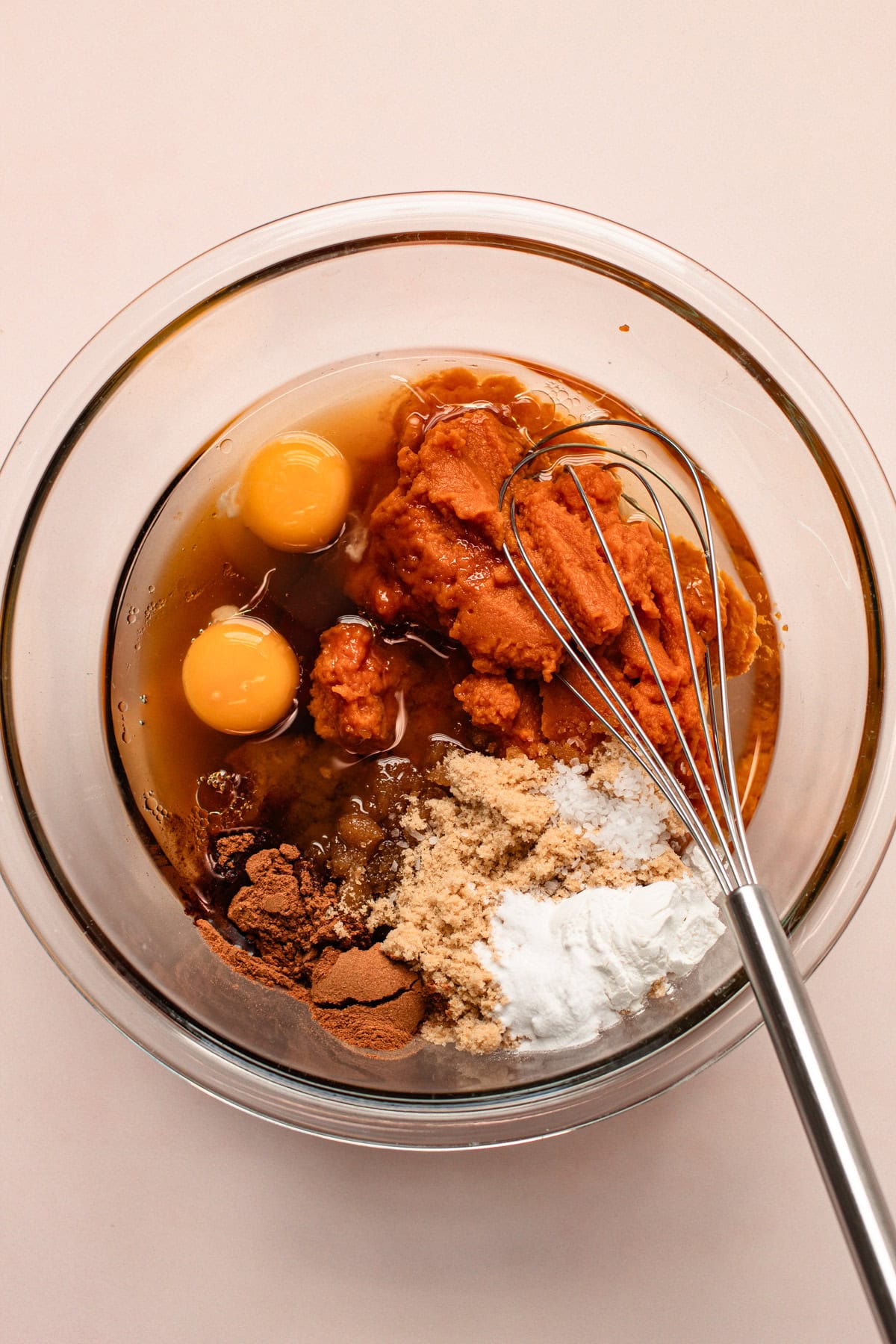 Mixing bowl filled with ingredients for whole wheat pumpkin bread, ready to be whisked.