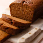 Sliced pumpkin bread made with whole wheat, arranged on a marble cutting board with a knife nearby.