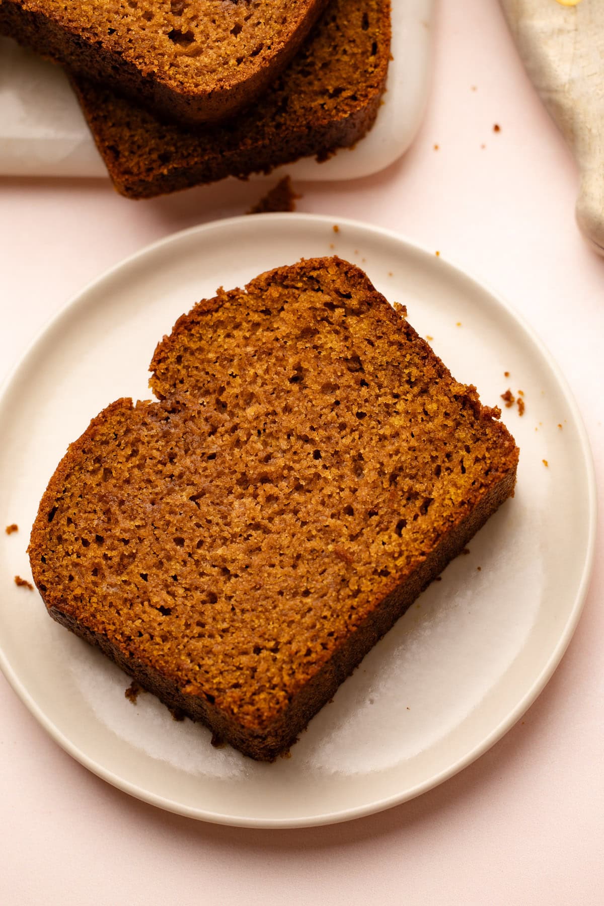 A thick slice of pumpkin bread whole wheat resting on a white plate, showcasing the dense crumb.