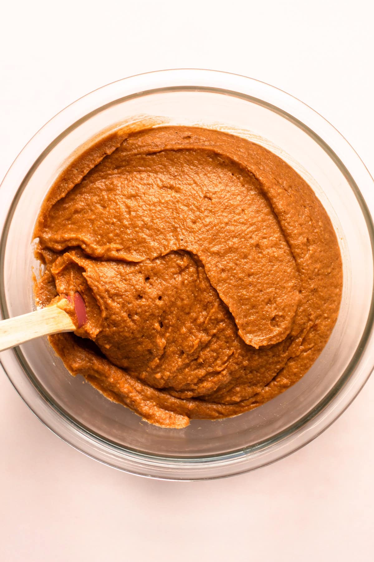 Smooth pumpkin bread whole wheat batter mixed in a glass bowl with a spatula.