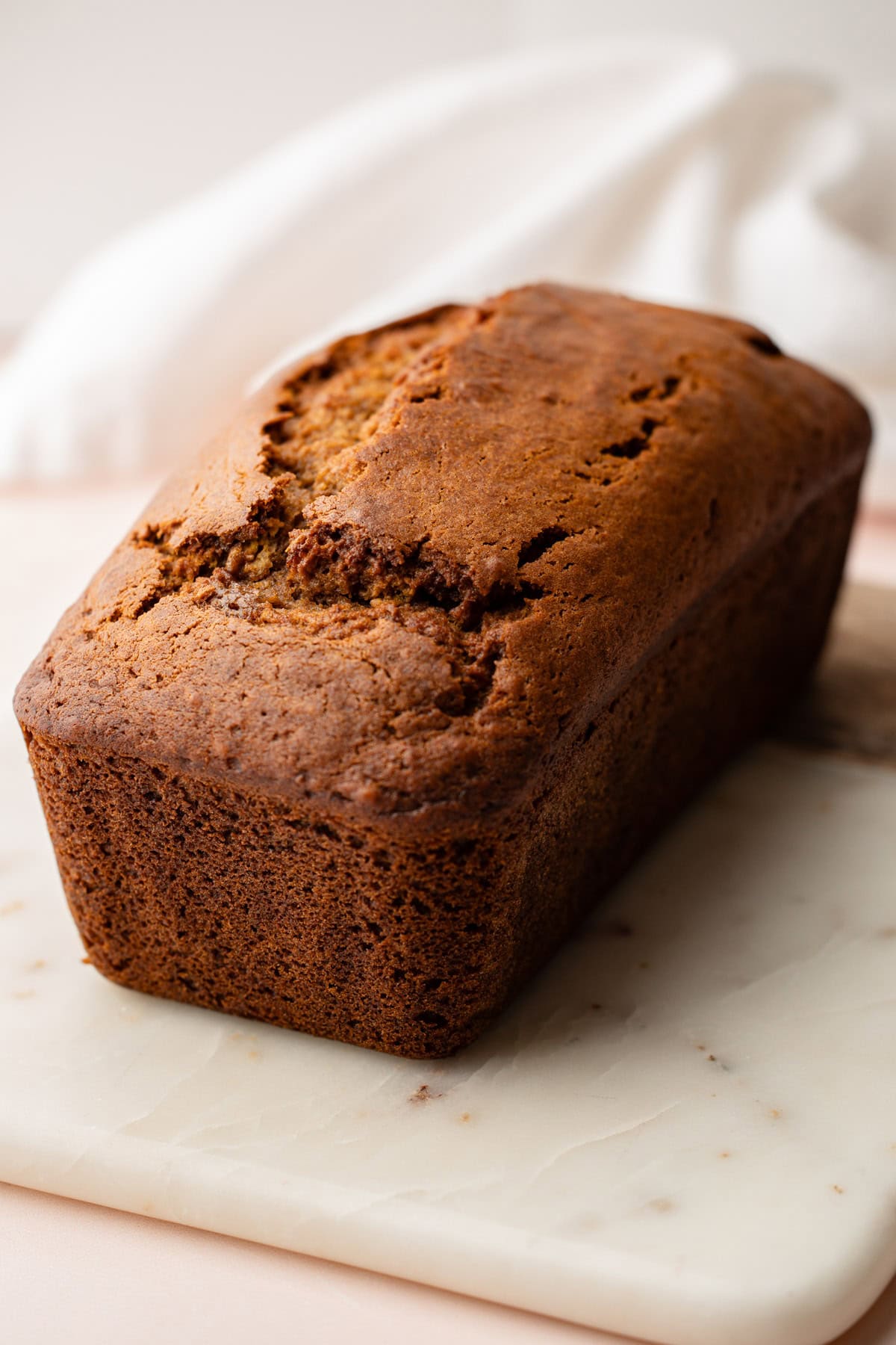 Close-up of a freshly baked whole wheat pumpkin bread loaf on a marble board.