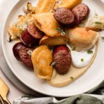 A plate of sheetpan baked pierogi recipe with sausage, cabbage and apples.