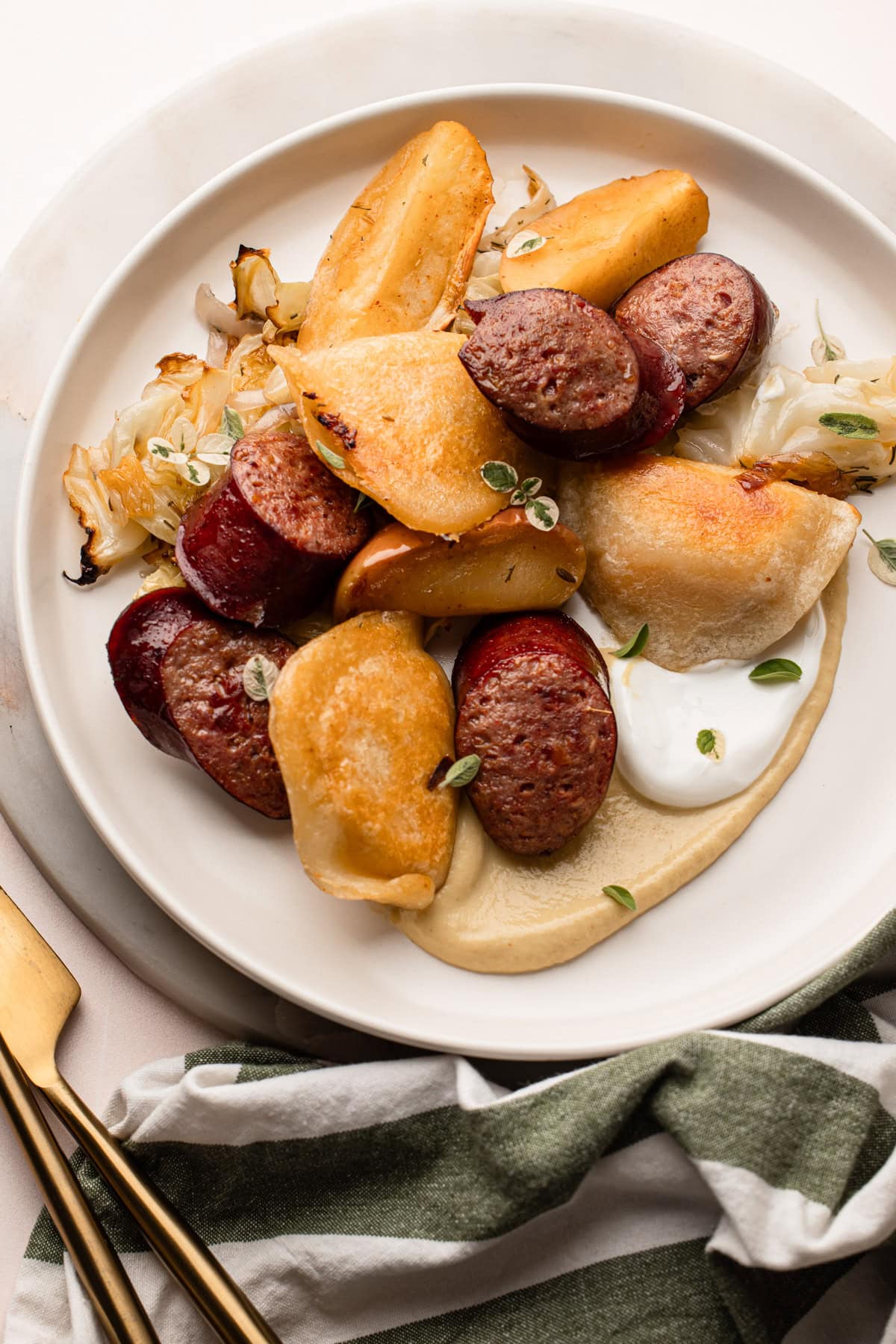 A plate of sheetpan baked pierogi recipe with sausage, cabbage and apples.