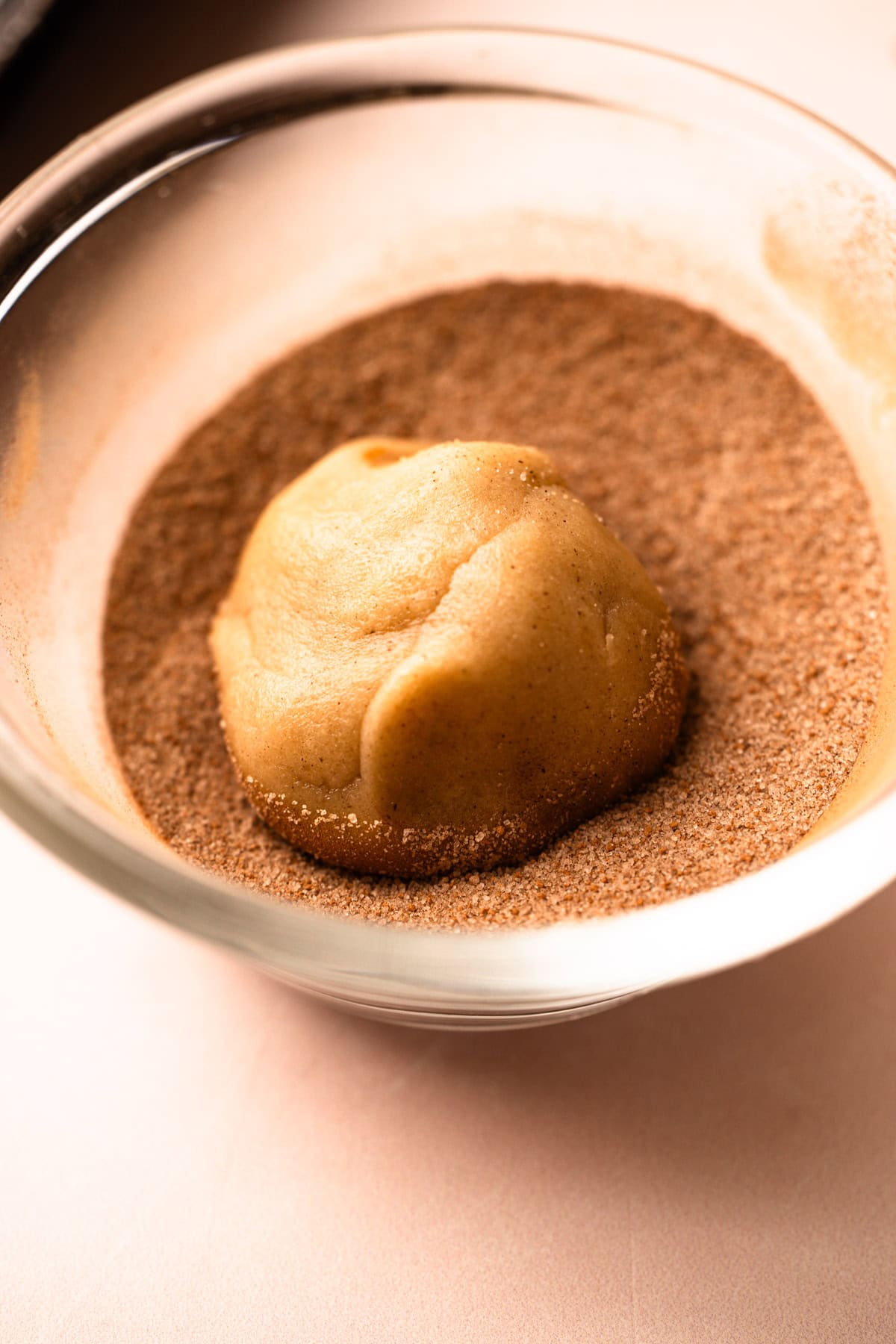 A ball of snickerdoodle dough coated in cinnamon sugar.