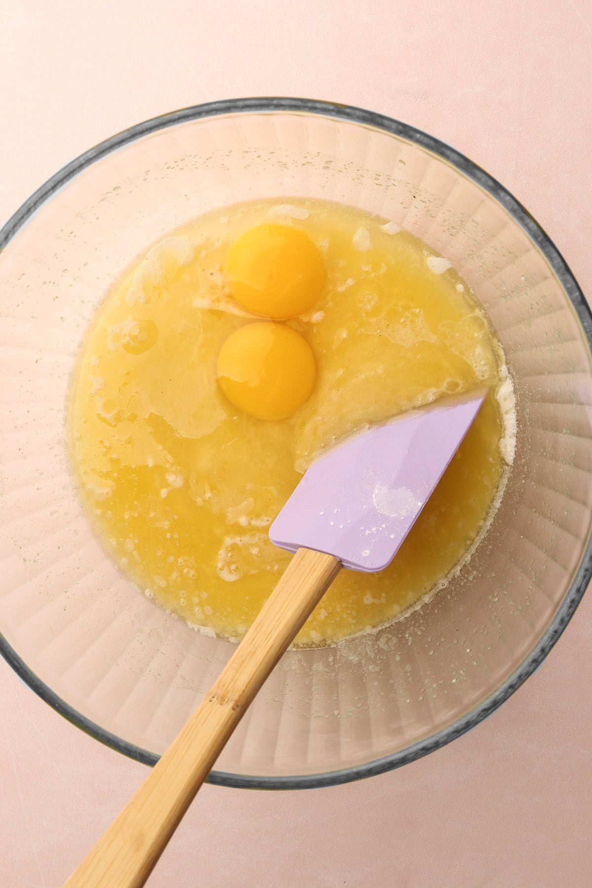 A mixing bowl with eggs and melted butter for a snickerdoodle cookie recipe.