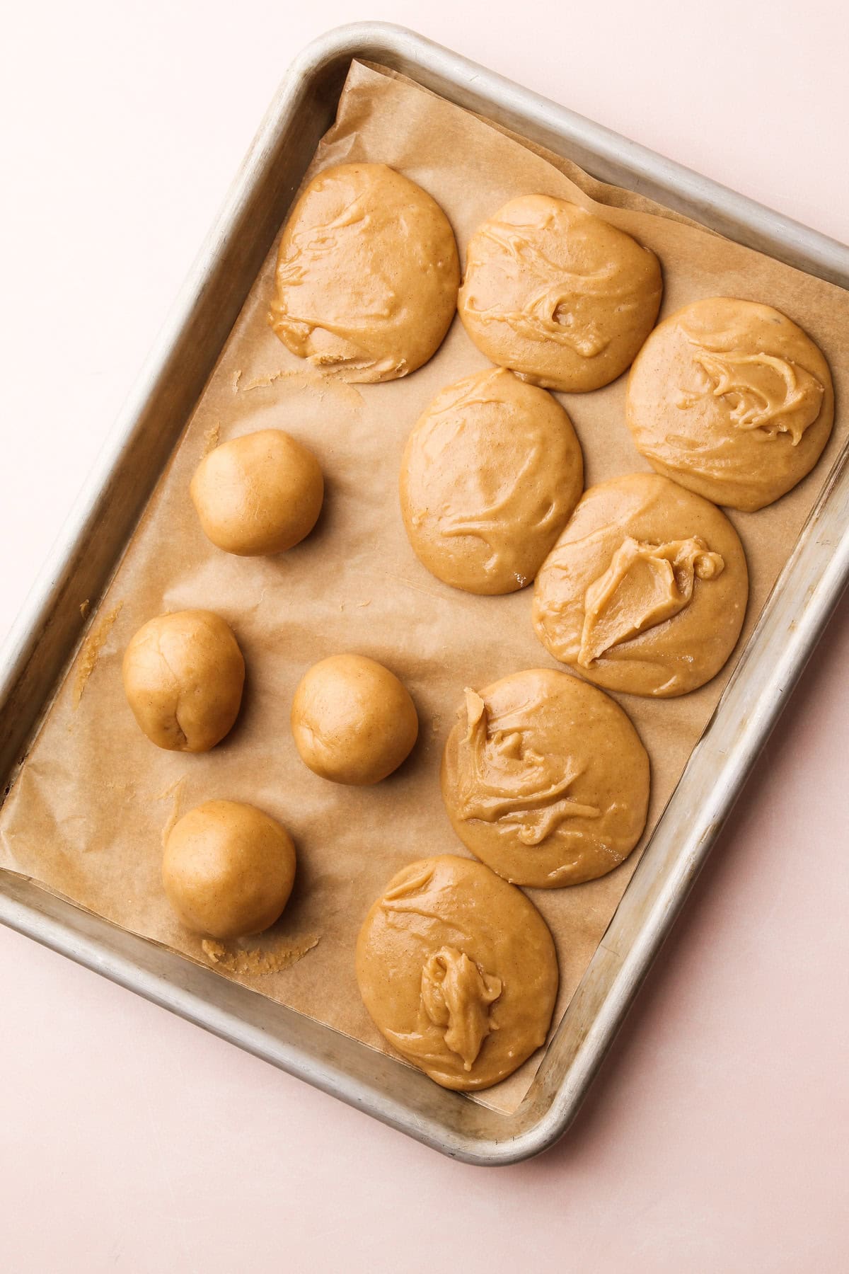 Dough balls and flattened cookies ready to bake for a snickerdoodle cookie recipe.