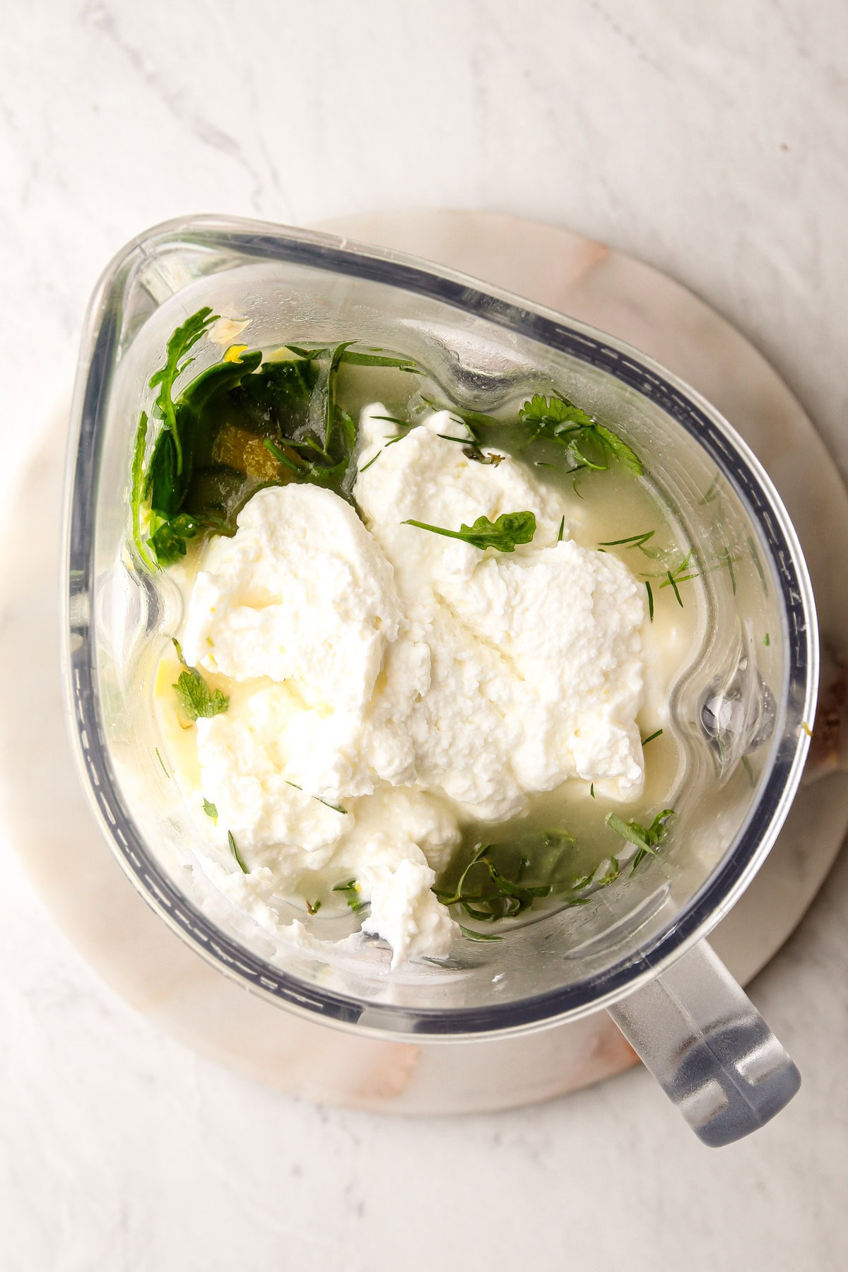 Soup made with green veggies and herbs in a blender before pureeing.