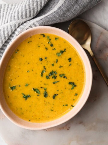 A serving of winter squash soup in a pink bowl.