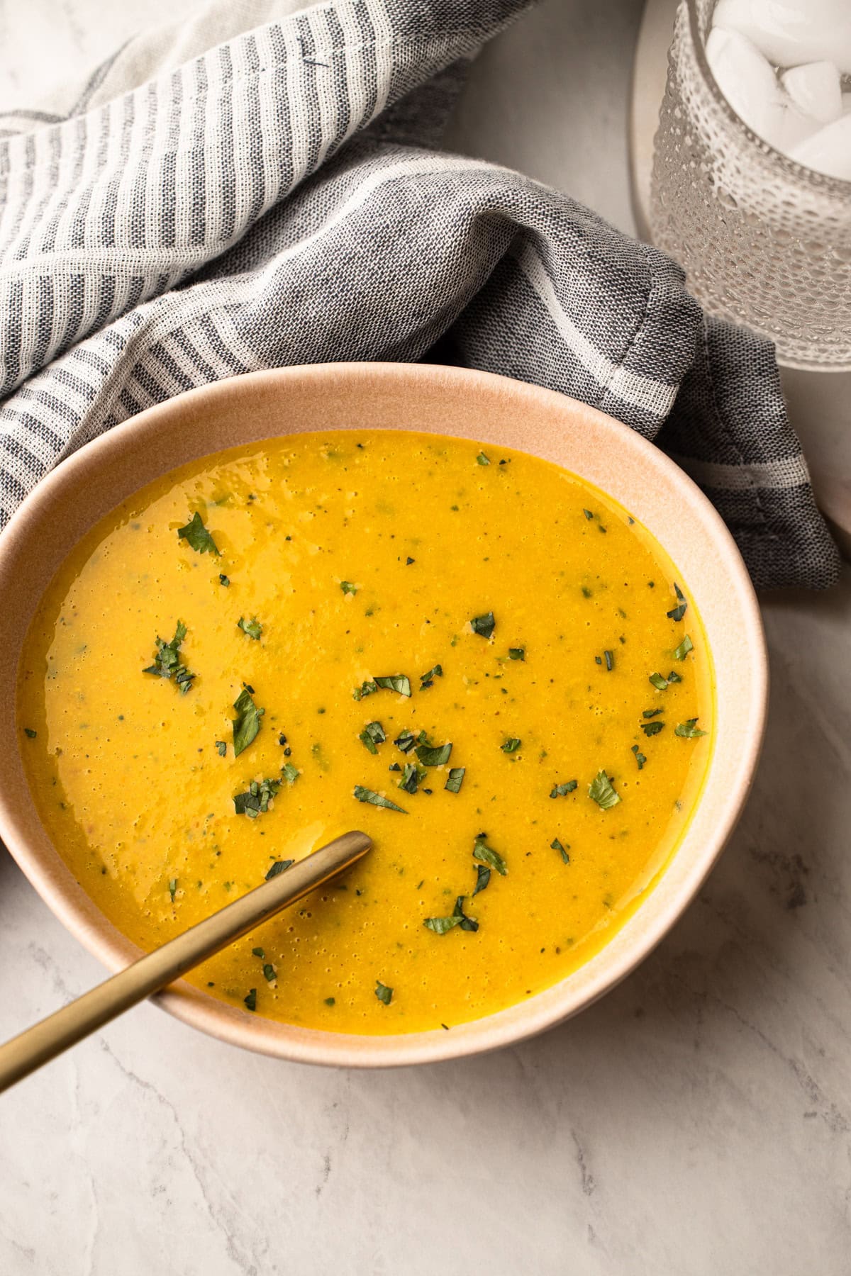 A serving of winter squash soup in a pink bowl.