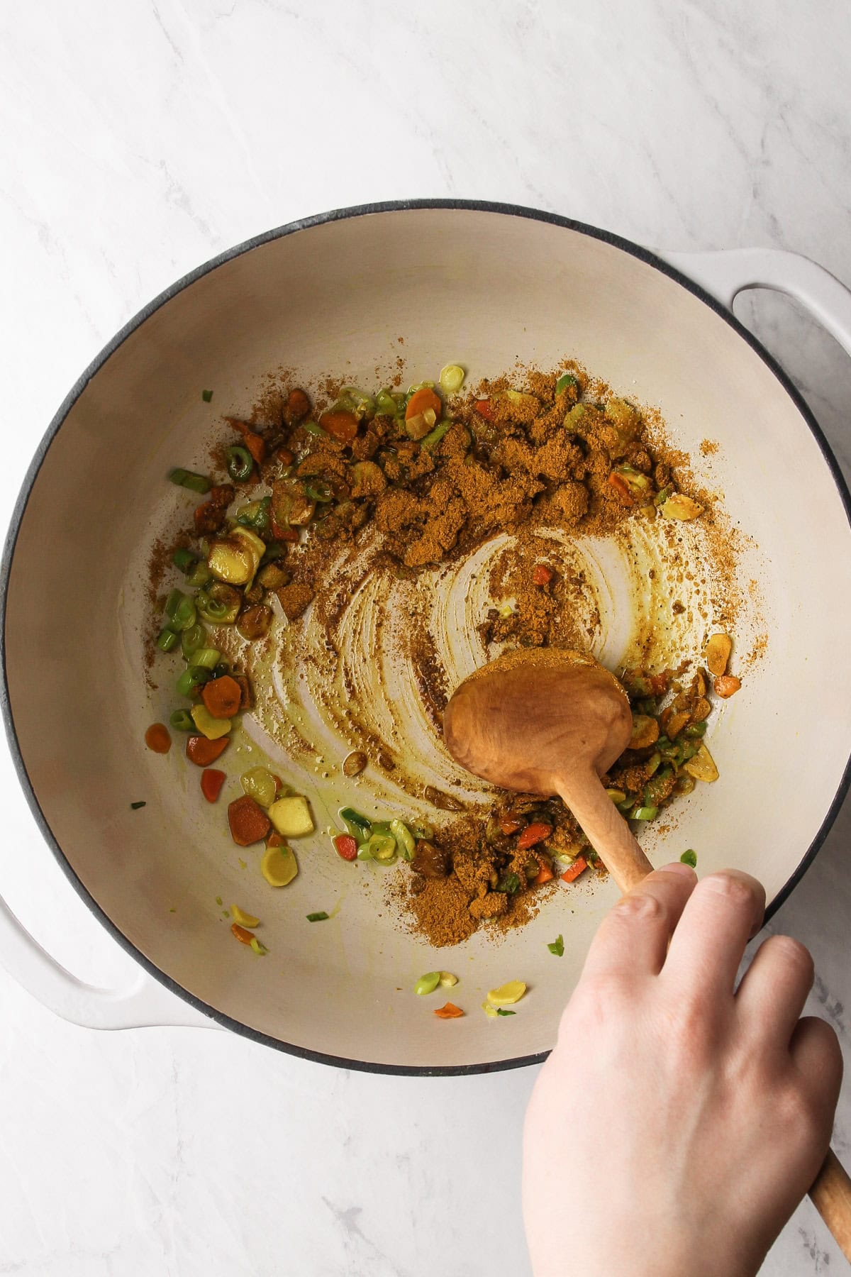 Sauteing green onions, turmeric and ginger in a pot with curry powder.