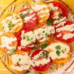 A tomato salad with a simple mayo dressing drizzled over the top with fresh herbs.
