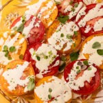 A creamy tomato salad with fresh herbs on a plate.