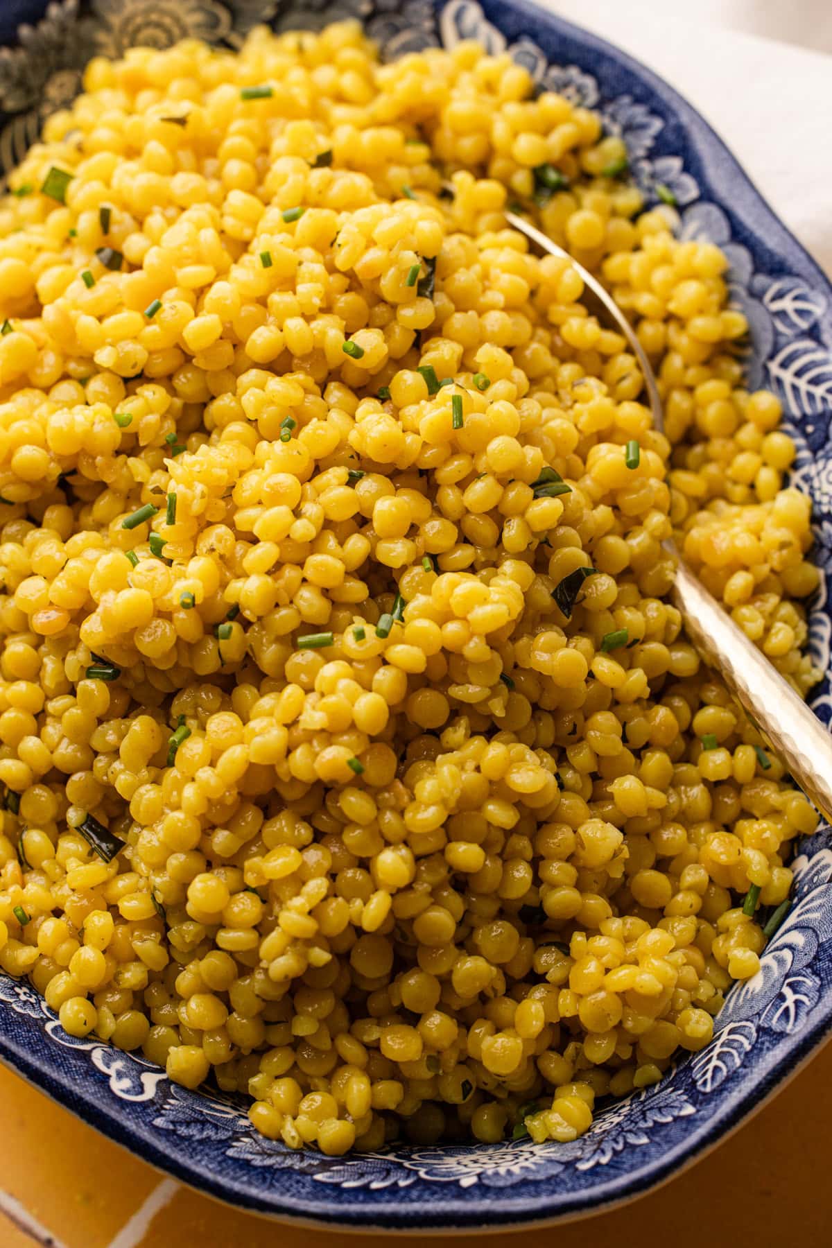 A large serving bowl filled with garlic and herb pearled couscous.