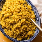 A large serving bowl filled with garlic and herb pearled couscous.