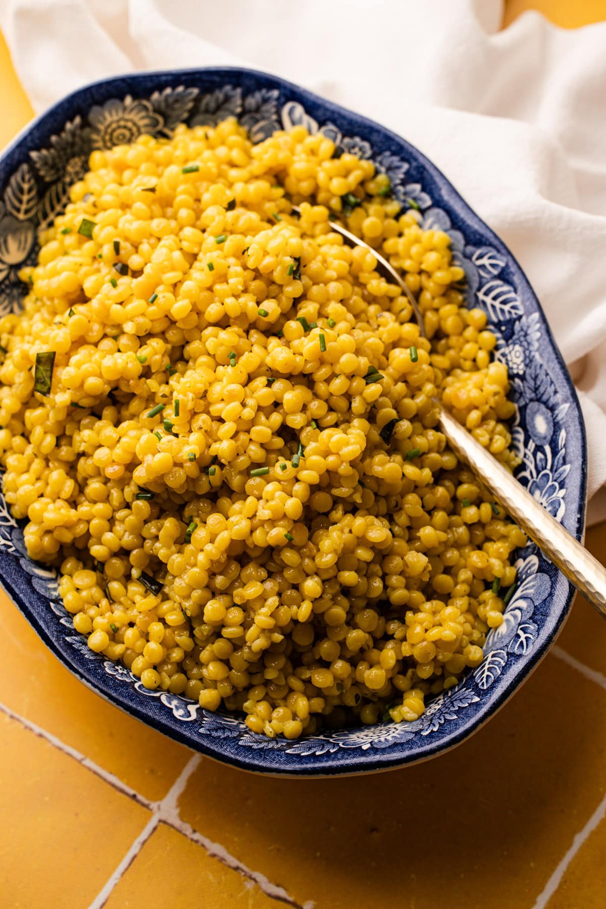 A large serving bowl filled with garlic and herb pearled couscous.