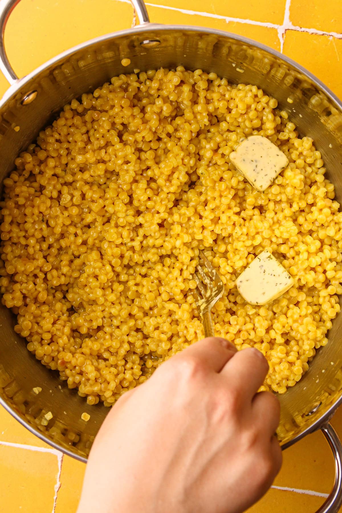 Using a form to fluff up cooked pearled couscous.