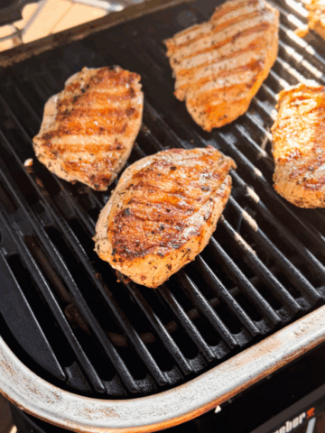 Fully cooked juicy grilled chicken breasts outside in the bright sun.