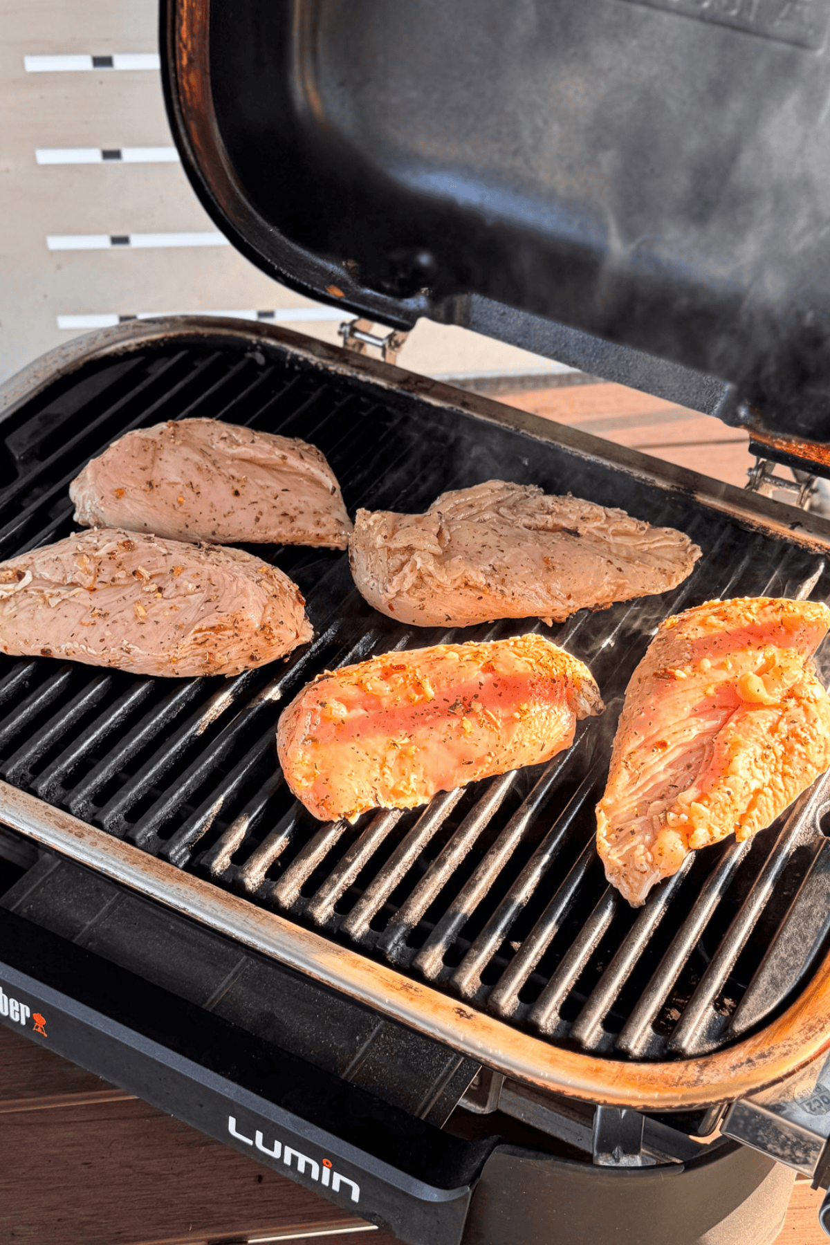 Raw chicken breasts cooking on a very hot grill.