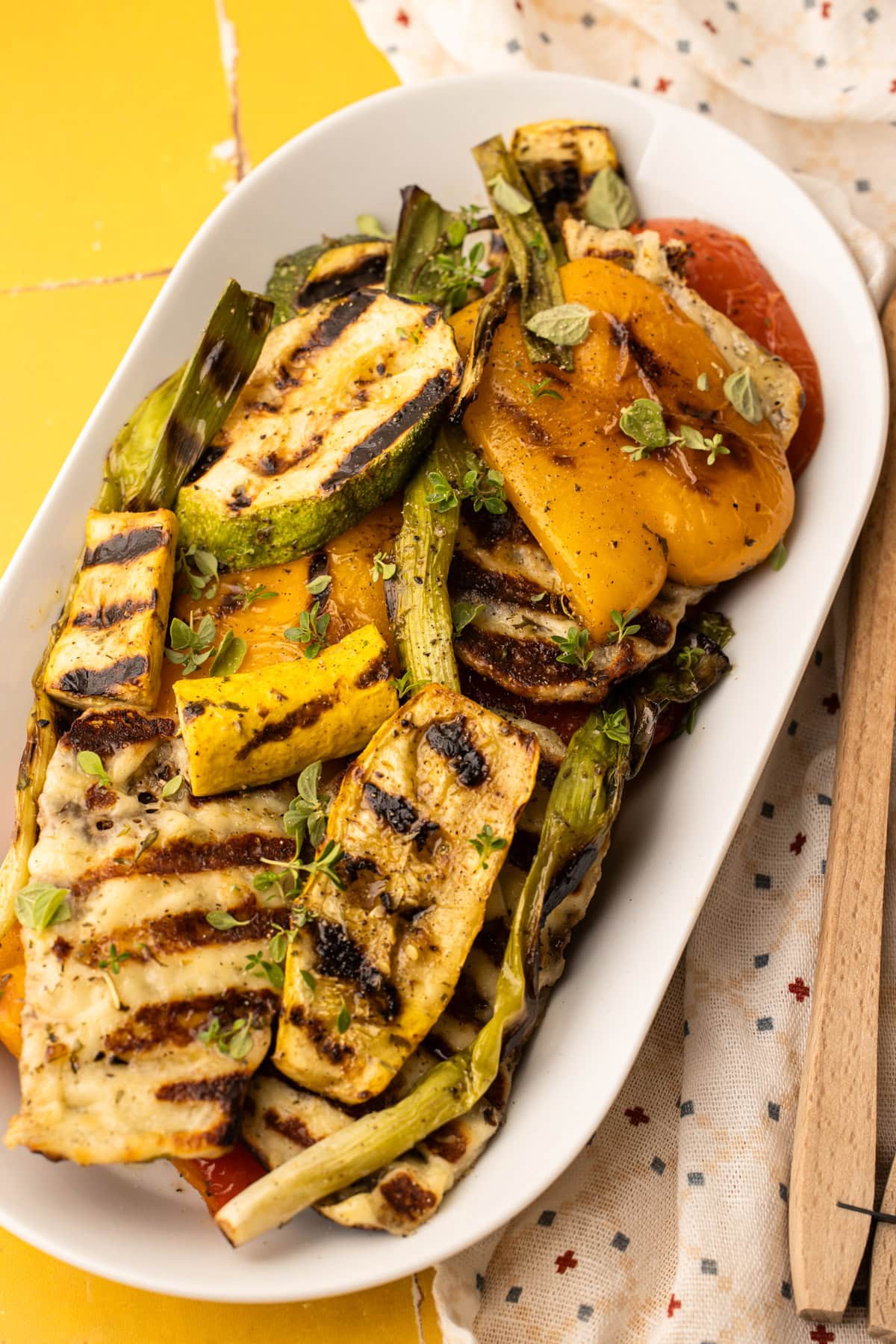 A serving platter filled with perfectly grilled veggies and halloumi with a sprinkle of fresh herbs on top.