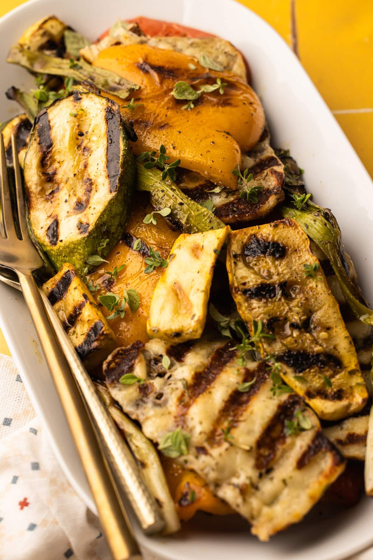 A serving platter filled with perfectly grilled veggies and halloumi with a sprinkle of fresh herbs on top.