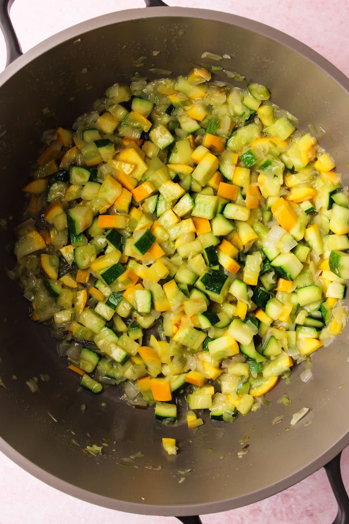 Zucchini cooking in a pot with onions for a one-pot pesto zucchini orzo.