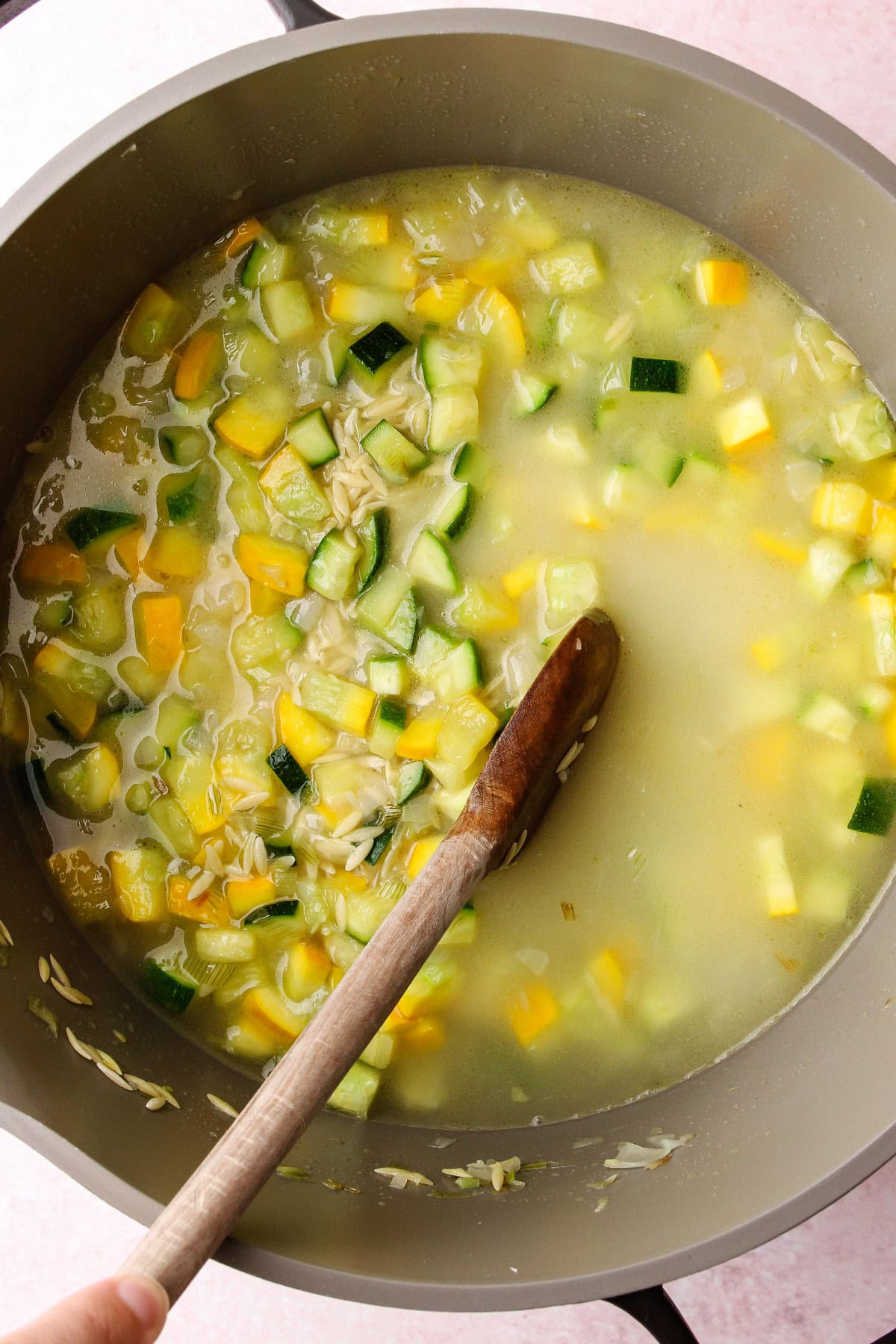 Assembling a one-pot pesto zucchini orzo pasta dish.