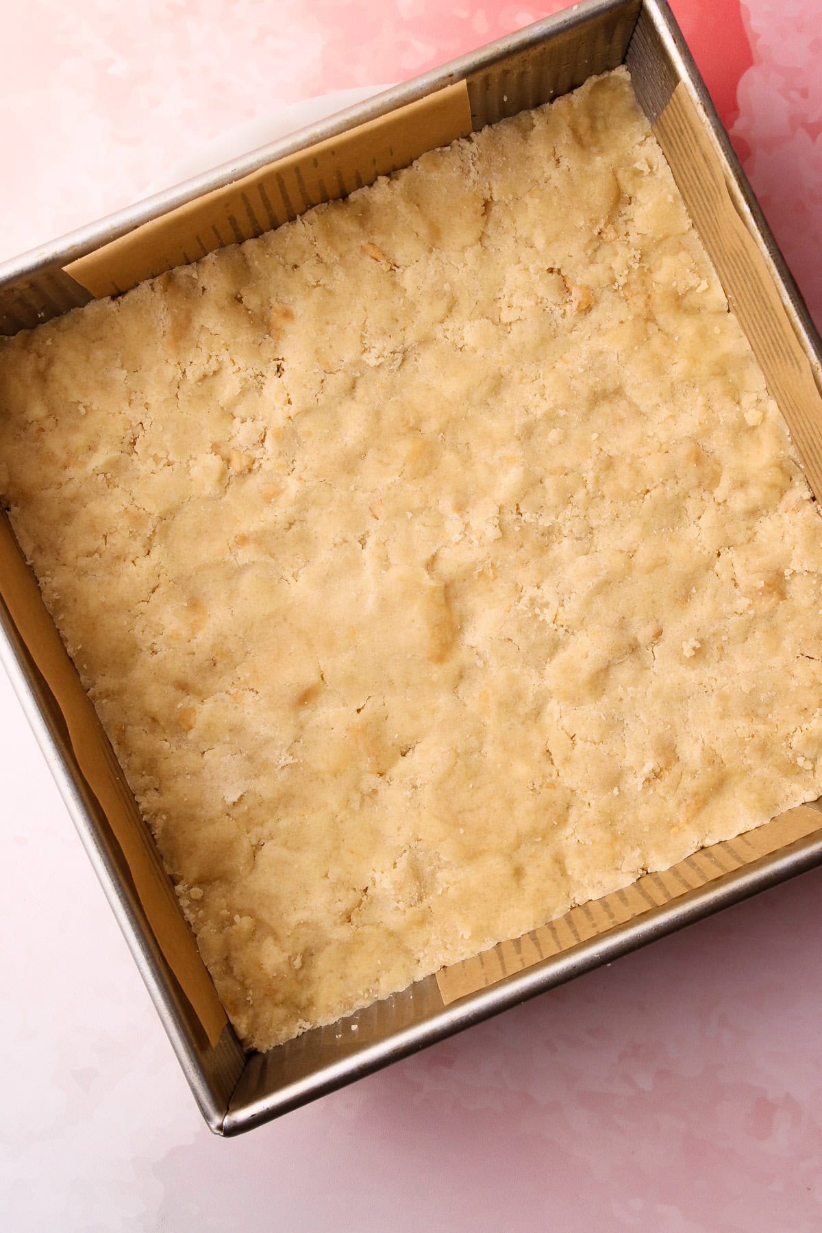 The crumble mixture patted down as the crust layer for strawberry crumble bars.