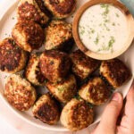 A serving platter of zucchini turkey meatballs with a creamy dipping sauce.
