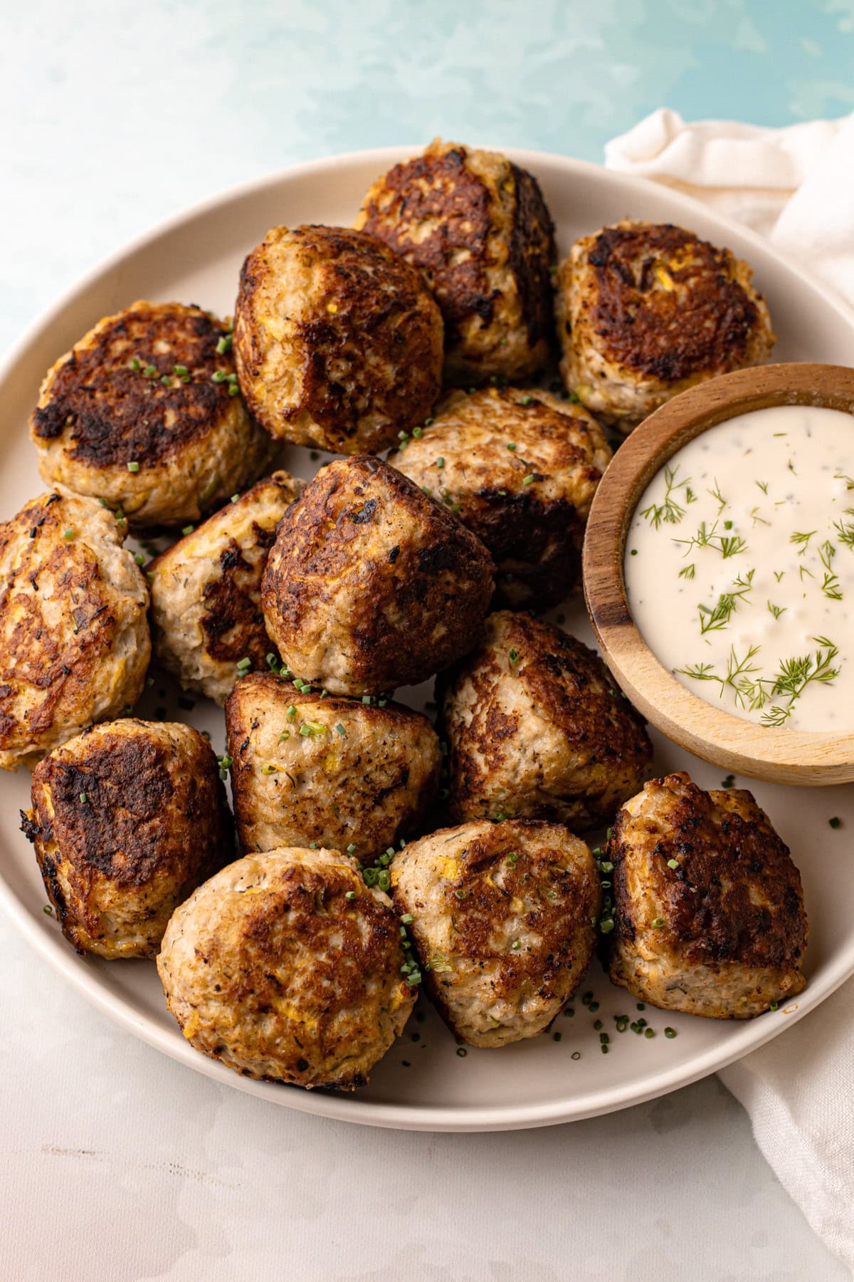 A serving platter of zucchini turkey meatballs with a creamy dipping sauce.