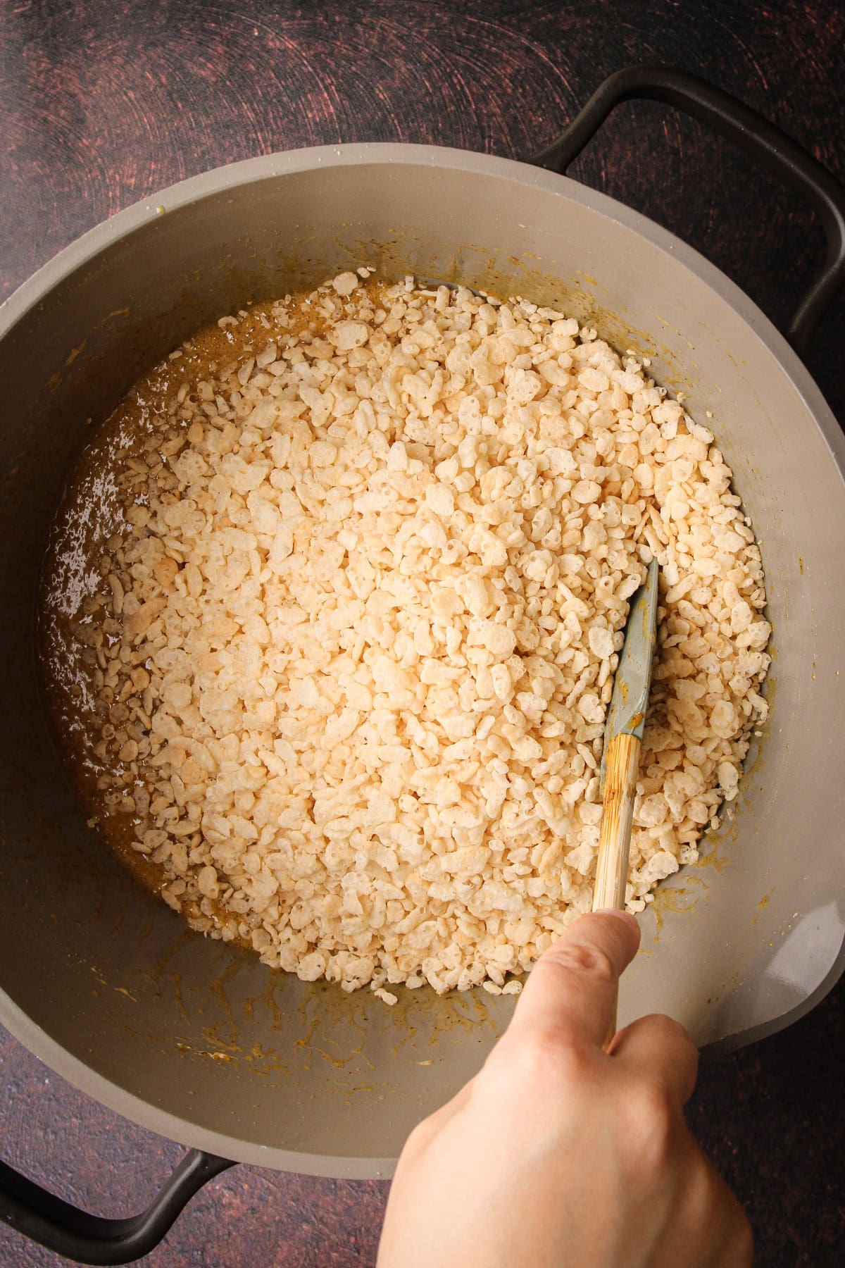 Melted marshmallows, pumpkin and butter with rice krispies cereal to prepare for pumpkin rice crispy treats.