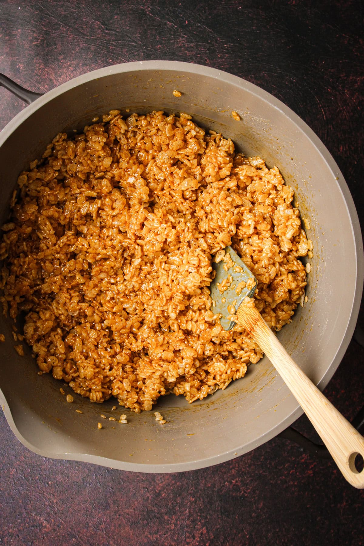 Mixing together pumpkin rice crispy treats in a pot.