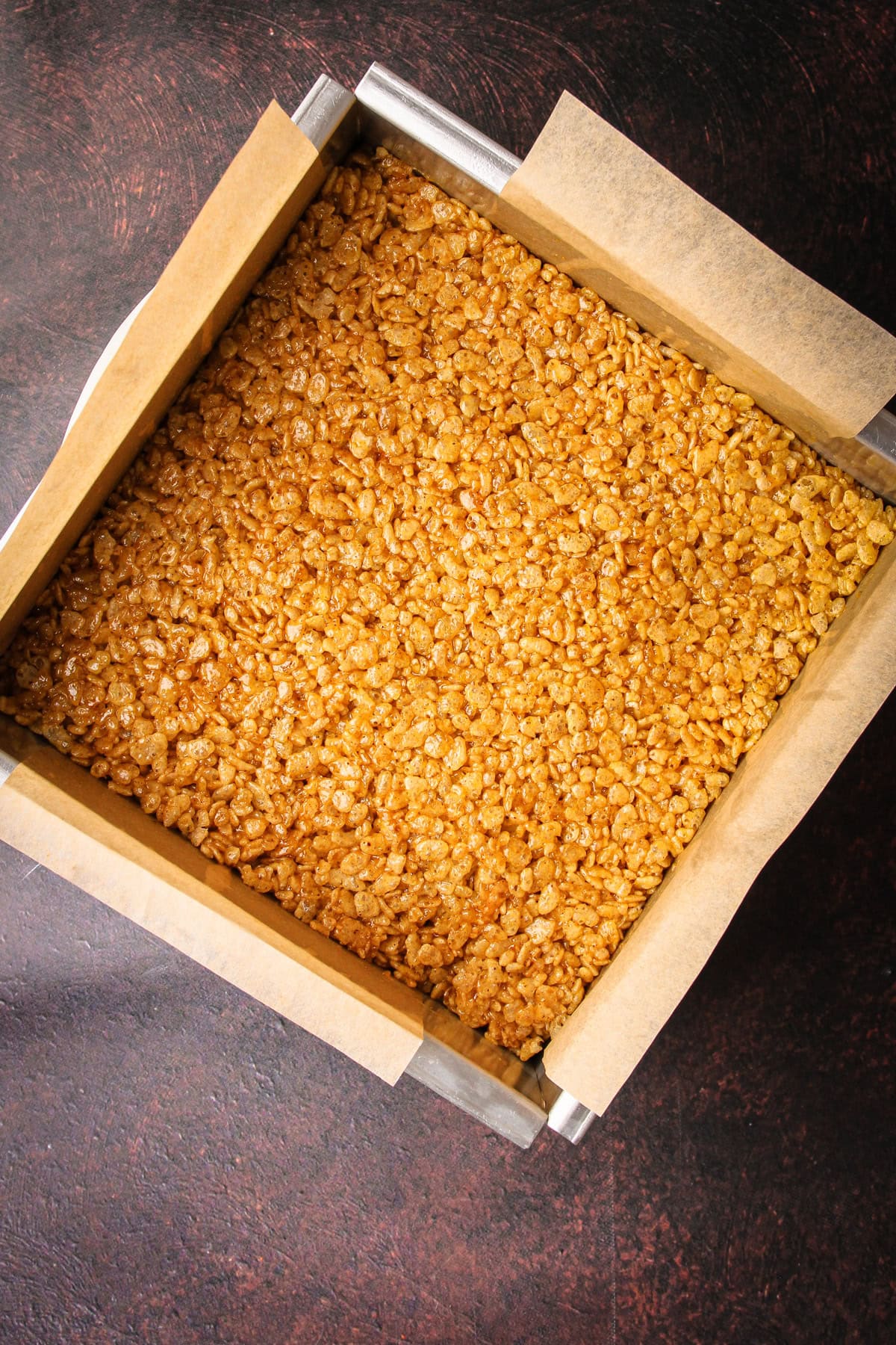 Prepared pumpkin rice crispy treats cooling in a pan.
