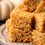 A batch of pumpkin rice crispy treats slice and served on a platter.