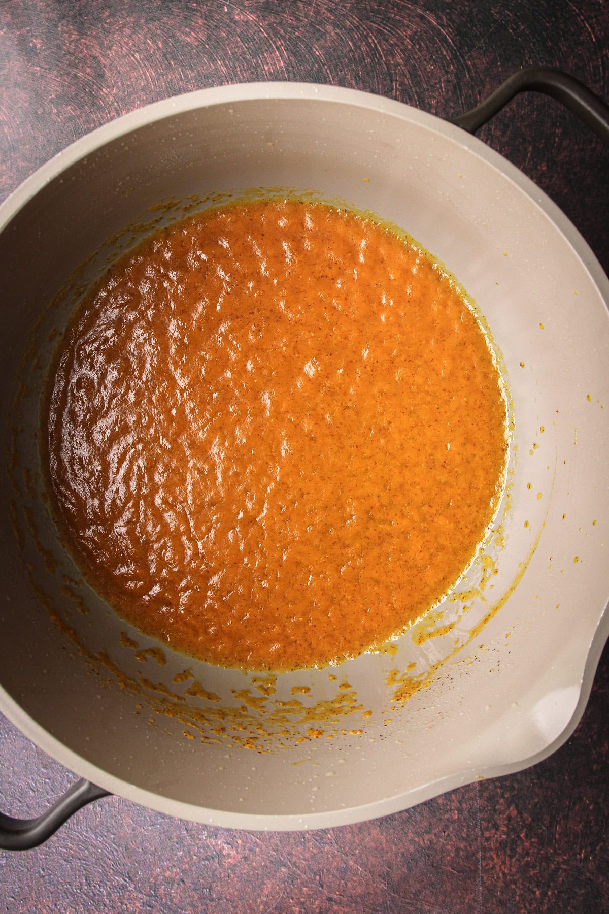 Pumpkin puree in a pot being cooked down to evaporate moisture.
