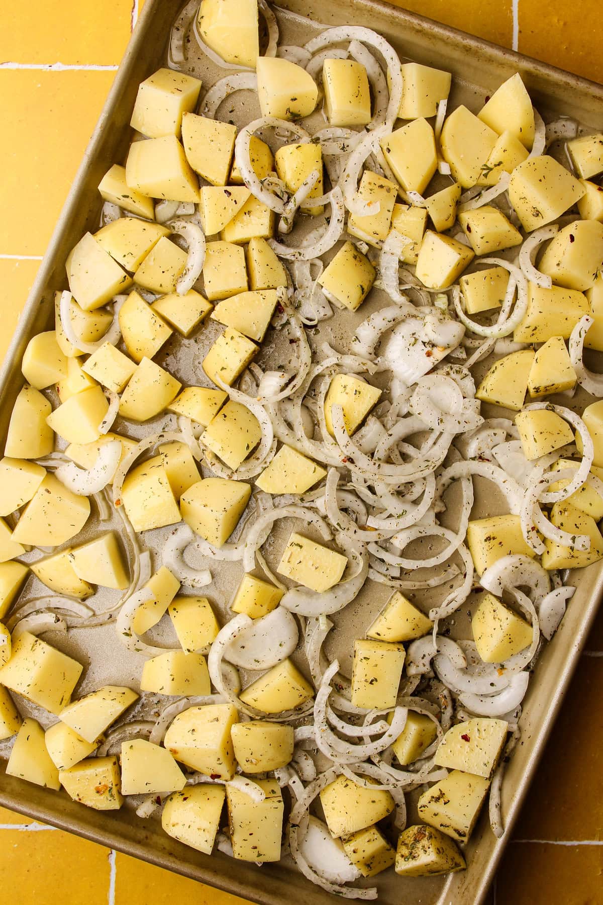 Potatoes and onions arranged on a sheet pan.