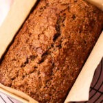A golden high risen crackly topped zucchini bread still in the bread pan.