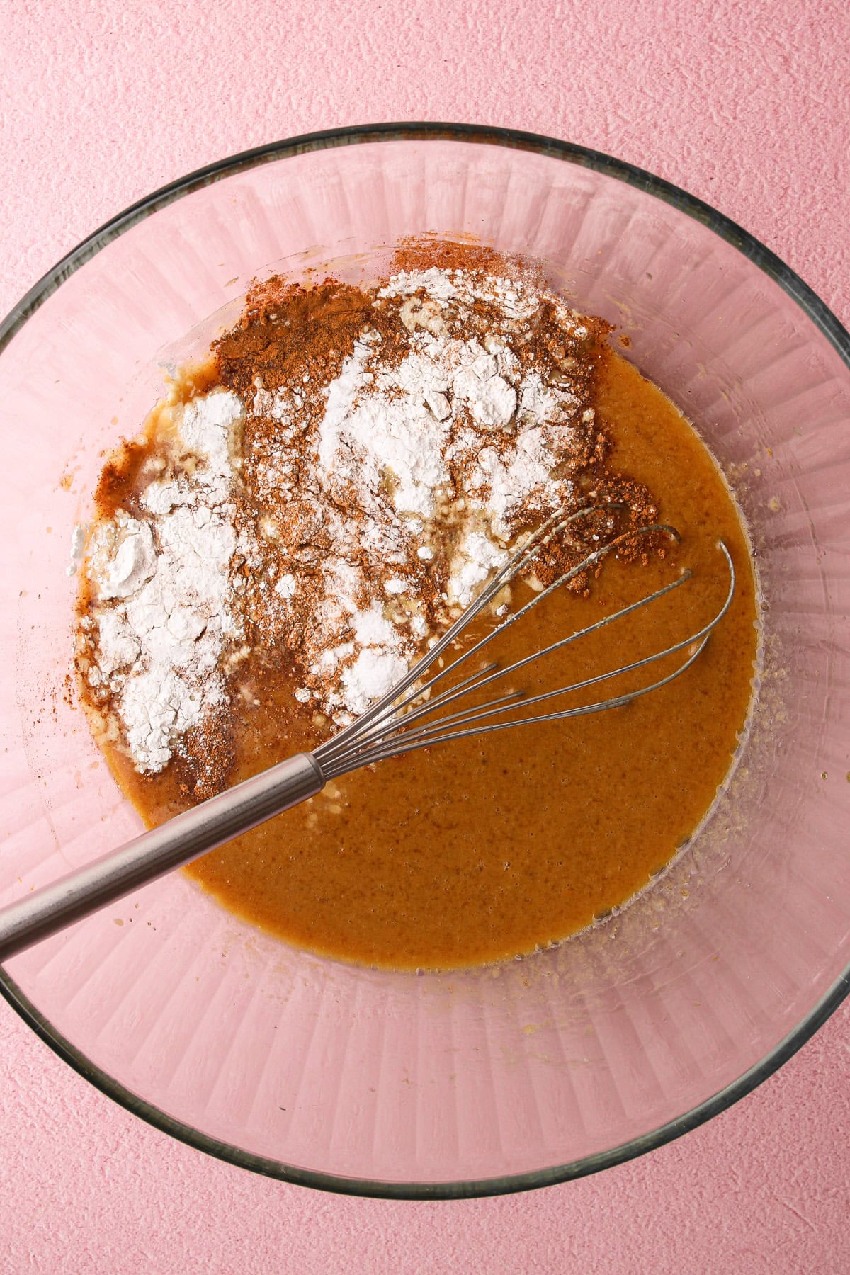 A bowl with the whisked wet ingredients and the spices for zucchini bread.