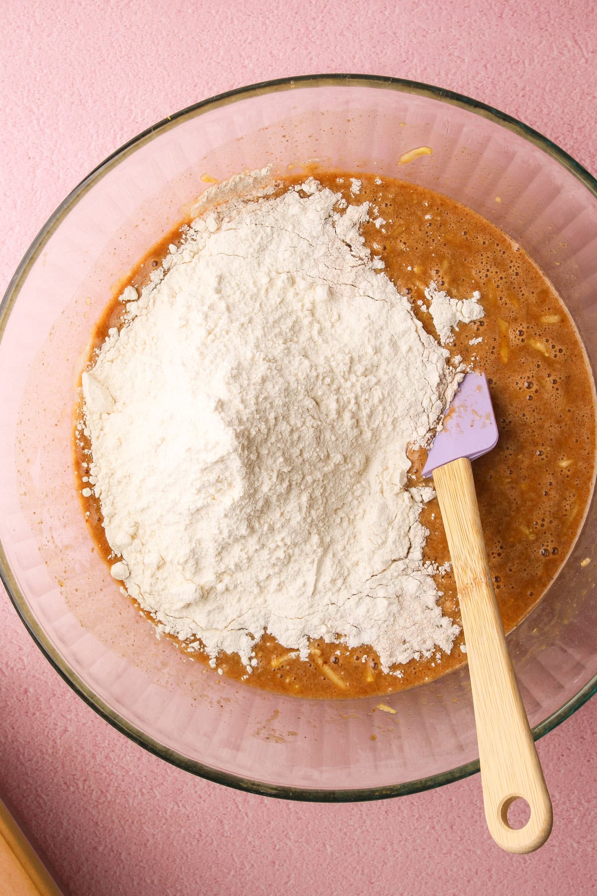 Flour on top of the whisked wet ingredients to make zucchini bread.